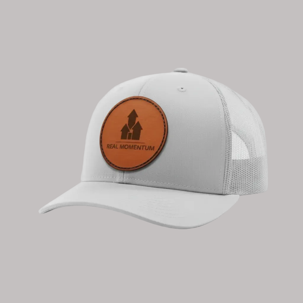 Gray cap with a brown leather patch featuring 'Real Momentum' logo on a white background